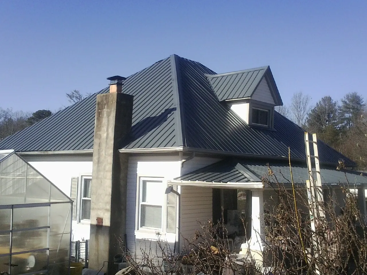 Dark blue standing seam metal roof on a white farmhouse with dormer — Slate & Tile Roof Repair by Roofing Brothers in Beyer