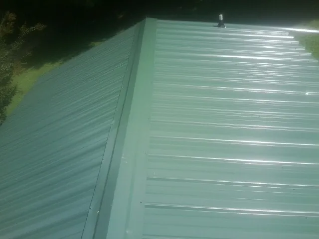 New green metal panels meeting at the ridge of a roof — Flat Roof Repair work by our crew in Beyer