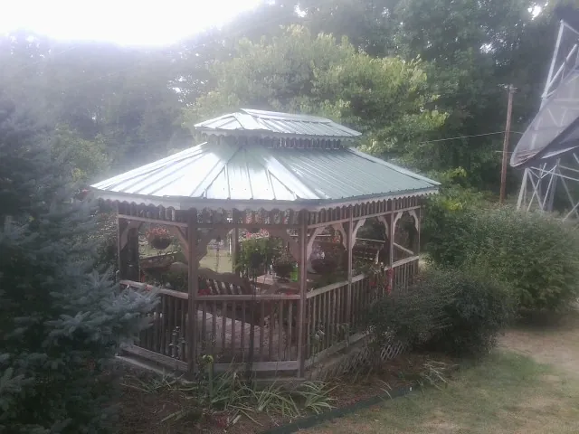 Green metal roof on a backyard gazebo surrounded by garden beds in Beyer