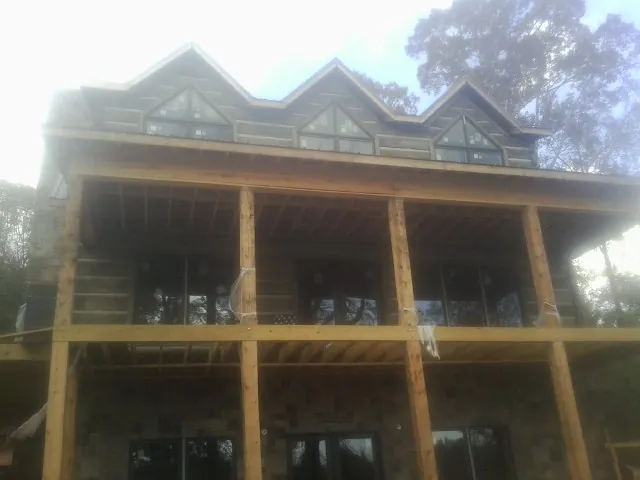 Dormers and porch framing on a large log home under construction — Roof Coating work by our crew in Beyer