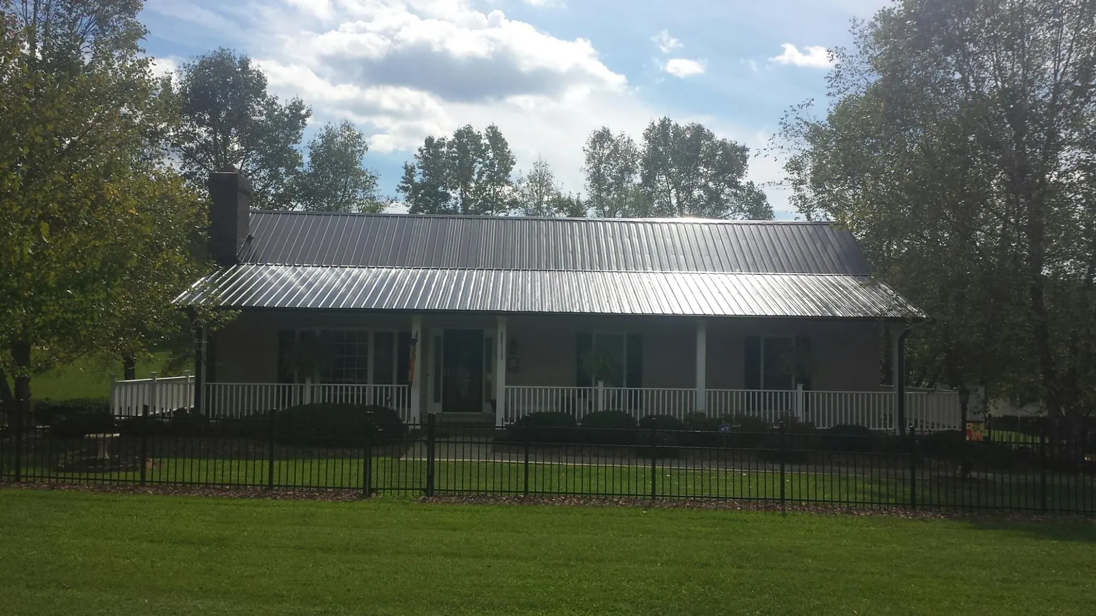 Gray metal roof on a brick ranch with a full width front porch — Gutter Guard Installation work by our crew in Beyer
