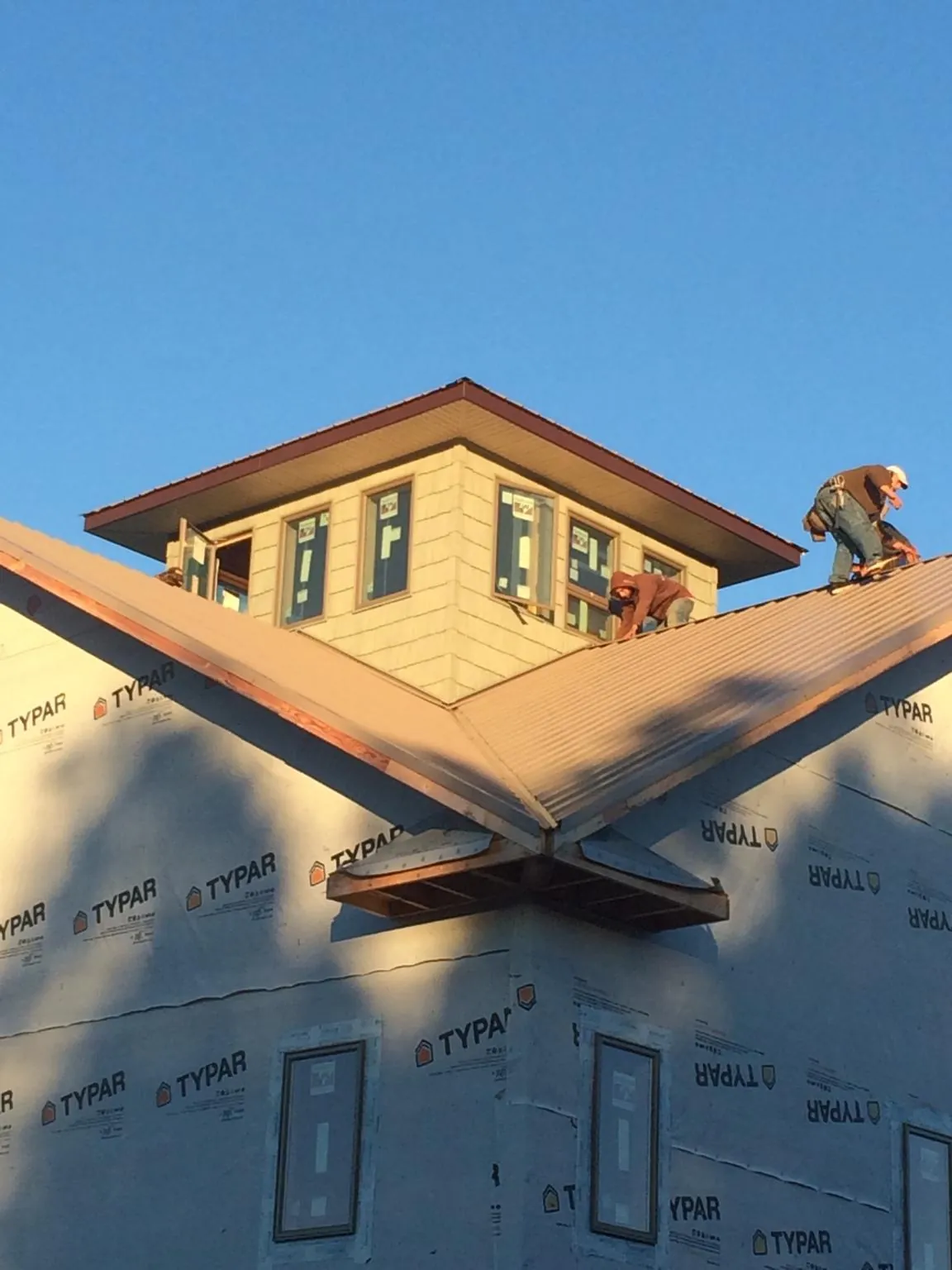 Roofers working around a rooftop cupola on a new metal roof at sunset — Roof Waterproofing in Beyer by Roofing Brothers